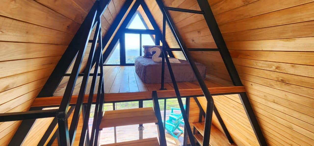 Upper loft A-frame cabin bed triangular window Blue Zone mountains luxury vacation rental Costa Rica retreat