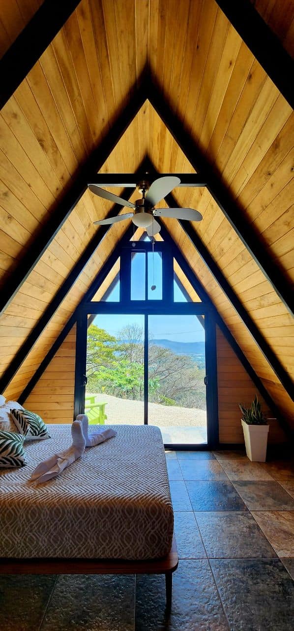 A-frame bedroom triangular window mountain views geometric bedding luxury vacation rental Costa Rica upscale comfort