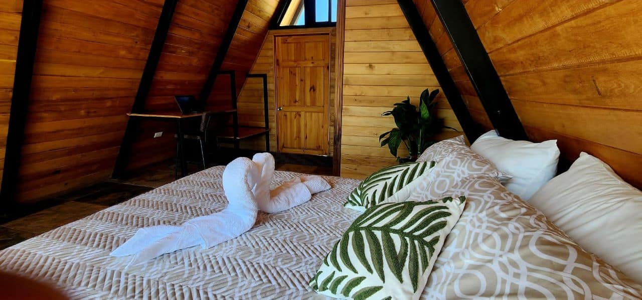 Cozy A-frame bedroom wooden walls decorative towels plants luxury vacation rental Costa Rica exclusive stay experience