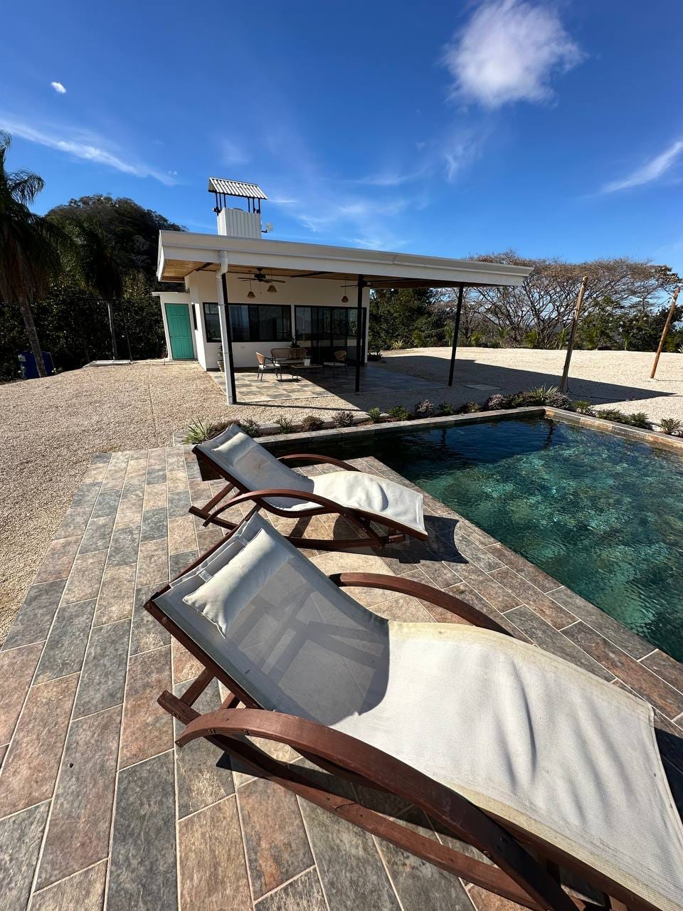 Pool area lounge chairs main lodge blue sky exclusive vacation spot luxury rental Costa Rica mountain retreat