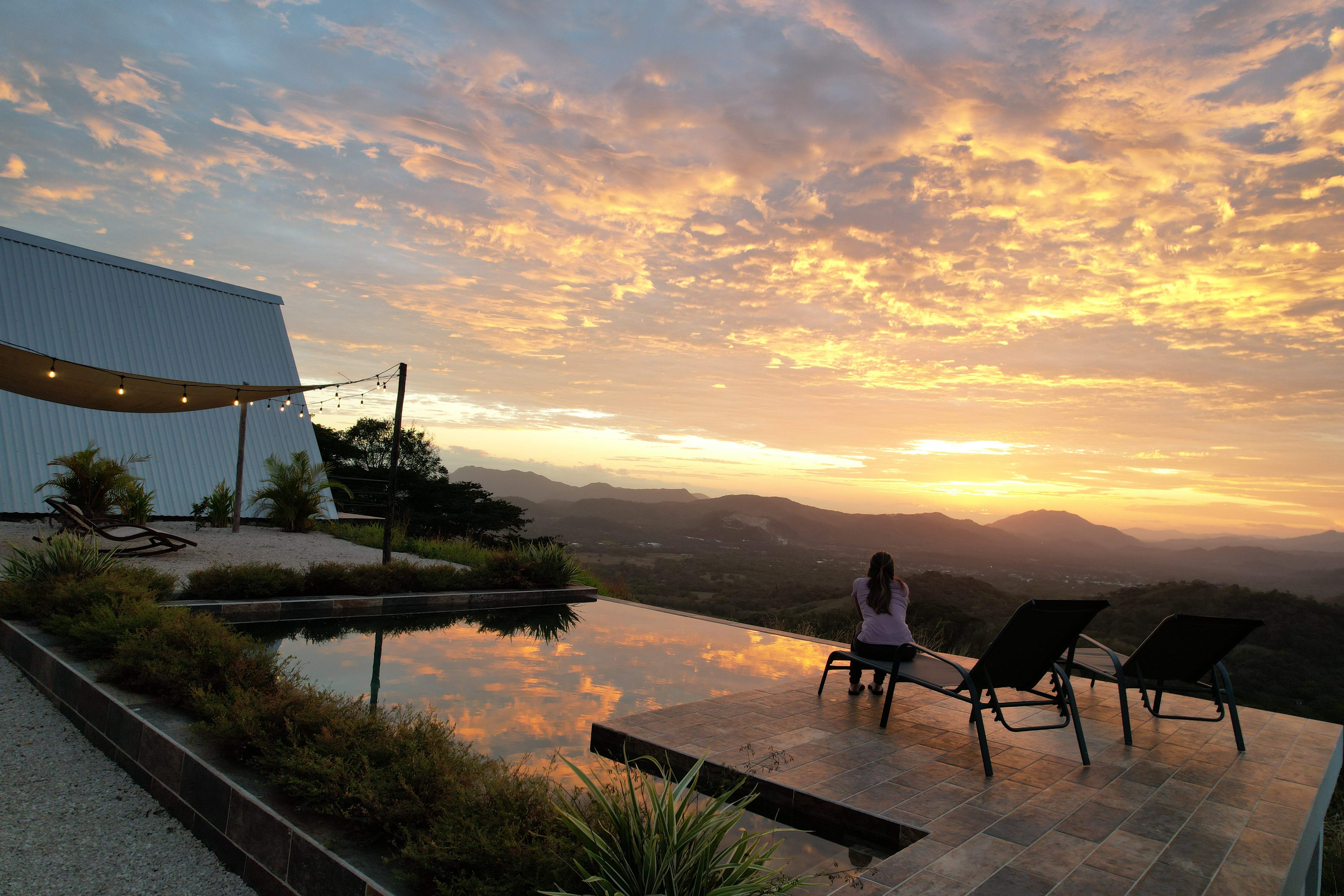 Person enjoying sunrise infinity pool panoramic view luxury Costa Rica vacation rental mountain retreat